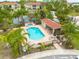 Aerial view of a community pool area with lounge chairs, a covered patio, and lush tropical landscaping at 5041 Royal Palms Way # 203, New Port Richey, FL 34652