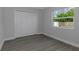 A brightly-lit bedroom has wood-look floors and a window with green outdoor views at 5214 Idlewild St, New Port Richey, FL 34653