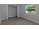 The bedroom has an open closet, wood-look floors and a window with outdoor views at 5214 Idlewild St, New Port Richey, FL 34653