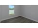 A bright bedroom features gray wood-look floors and a window with outdoor views at 5214 Idlewild St, New Port Richey, FL 34653