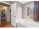 Bathroom with a large soaking tub and tiled surround, plus a view to the outdoors and a walk-in closet at 5422 Foley Sq, New Port Richey, FL 34652