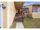 Welcoming front porch with wooden steps leading to a red front door and a decorative window at 5422 Foley Sq, New Port Richey, FL 34652