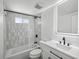 Modern bathroom featuring gray tile, sleek black fixtures, and a stylish, illuminated vanity mirror at 5512 Tropic Dr, New Port Richey, FL 34653