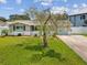 Traditional single-story home with a manicured lawn, mature trees, and a driveway leading to an attached garage at 5512 Tropic Dr, New Port Richey, FL 34653