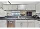 Charming kitchen with white cabinets, stainless steel appliances, and an open view into the bright living room at 6340 Spoonbill Dr, New Port Richey, FL 34652