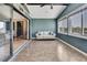 Bright sunroom with tile floor, white sofa, blue accent wall, and large sliding glass doors for indoor-outdoor living at 6340 Spoonbill Dr, New Port Richey, FL 34652
