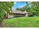 View of the backyard featuring a screened-in patio, lush green grass, and mature trees offering shade and privacy at 642 Erin Way, Brooksville, FL 34601