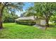 Image shows backyard with green grass and shed, surrounded by trees providing a private and serene outdoor space at 642 Erin Way, Brooksville, FL 34601