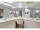 Bathroom featuring a vanity with dual sinks, mirrors, and a chair, offering a functional space at 6490 Pine Meadows Dr, Spring Hill, FL 34606