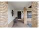 Inviting entryway featuring a wooden front door, brick columns, and covered porch at 6490 Pine Meadows Dr, Spring Hill, FL 34606