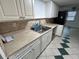 Functional kitchen featuring a stainless steel sink, white cabinets, and a view into the adjacent dining area at 7331 Sandalwood Dr, Port Richey, FL 34668