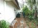 Backyard exterior with an air conditioner and chain link fence, along a leaf covered sidewalk at 7632 Lake Forest Cir, Port Richey, FL 34668