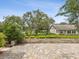 Backyard with brick patio featuring landscaped garden, lush green lawn, and shade trees in a peaceful setting at 8001 Summerbreeze Ter, Spring Hill, FL 34606