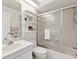 Bright bathroom featuring a shower/tub with sliding glass doors, white toilet, sink and open shelving at 8001 Summerbreeze Ter, Spring Hill, FL 34606