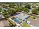 Aerial view of a home featuring a screened pool, a playground, and fenced yard in a tree-lined neighborhood at 8749 Aruba Ln, Port Richey, FL 34668