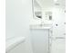 Bright, all-white bathroom with marble floors, sleek vanity with modern fixtures and a mirrored wall at 9200 Lunar Ln, Port Richey, FL 34668