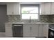Updated kitchen boasts stainless steel appliances, white cabinets, and stylish backsplash at 9200 Lunar Ln, Port Richey, FL 34668