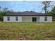 A home's back exterior features an open patio with sliding glass doors and a spacious grassy yard at 9482 Noddy Tern Rd, Weeki Wachee, FL 34613