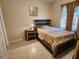 This cozy bedroom features a wooden bed frame, tile flooring, and soft, warm neutral decor at 954 Old Windsor Way, Spring Hill, FL 34609