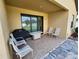 Covered patio with tiled floor and a grill, furniture and sliding glass doors at 954 Old Windsor Way, Spring Hill, FL 34609