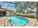 Screened-in pool with stairs into water and brick patio at 9757 Hermosillo Dr, New Port Richey, FL 34655