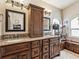 Elegant bathroom with dual sinks, granite countertops, dark wood cabinetry, and decorative mirrors at 2255 Long View Cir, Brooksville, FL 34604