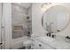 Bathroom with tiled shower, tub, and round mirror over a marble countertop vanity with black fixtures at 10645 Garda Dr, Trinity, FL 34655