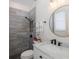 Stylish bathroom featuring a tiled shower, decorative mirror, marble countertop, and black fixtures at 10645 Garda Dr, Trinity, FL 34655