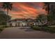 Elegant home boasting a tile roof, manicured landscaping, circular driveway, and a grand entrance under a fiery sky at 10645 Garda Dr, Trinity, FL 34655