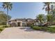 Eye-level view of a attractive home featuring lush landscaping, a spacious brick driveway, and a three-car garage at 10645 Garda Dr, Trinity, FL 34655