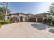 Stunning home showcasing an expansive brick driveway leading to a three-car garage and lush landscaping under a clear blue sky at 10645 Garda Dr, Trinity, FL 34655