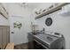 Organized laundry room with gray washer/dryer, cabinets, shelving, and decorative accents at 10645 Garda Dr, Trinity, FL 34655