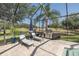 Outdoor screened-in pool area featuring stone patio with lounge chairs and built-in grill at 10645 Garda Dr, Trinity, FL 34655