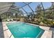 Large screened in pool with ample seating, lush landscaping and view of trees at 10645 Garda Dr, Trinity, FL 34655
