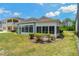 Spacious backyard with trimmed shrubbery, a sunroom, and freshly cut grass on a sunny day at 11401 Quiet Forest Dr, Tampa, FL 33635