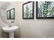 Stylish powder room with a pedestal sink, round mirror, and nature-themed framed art creating a serene ambiance at 11410 Spectacled Dr, New Port Richey, FL 34654