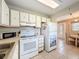 Classic kitchen featuring white cabinets, and appliances and an adjacent dining area at 11821 Boynton Ln, New Port Richey, FL 34654
