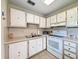 Traditional kitchen features white appliances and cabinets with tile backsplash and tile floors at 11821 Boynton Ln, New Port Richey, FL 34654
