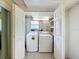 Functional laundry room with washer and dryer, open shelving, and double door access at 11821 Boynton Ln, New Port Richey, FL 34654