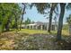 View of the house's back exterior, showcasing the screened-in pool area and mature trees at 12106 Bear Creek Ln, Hudson, FL 34667