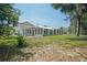 Back view of home with screened porch, mature trees, and large lot at 12106 Bear Creek Ln, Hudson, FL 34667