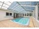 Enclosed pool area featuring tile flooring, a translucent roof, large windows, and a dining table at 12106 Bear Creek Ln, Hudson, FL 34667
