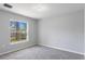 Bright bedroom featuring neutral carpet, gray walls, and a window with a lush, green yard at 12192 Eskimo Curlew Rd, Weeki Wachee, FL 34614
