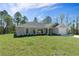 Well-maintained front yard of a single-story home with a grey exterior, lush lawn, and mature trees at 12192 Eskimo Curlew Rd, Weeki Wachee, FL 34614