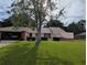 Charming single-story home with a well-manicured lawn and mature tree in a residential neighborhood, garage on the left side at 1221 Etta Ave, Spring Hill, FL 34609