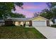 Charming single-story home with a well-manicured lawn, two-car garage and beautiful landscaping at sunset at 12411 Yorktown Ln, Hudson, FL 34667