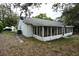Exterior view of the back of the home with a screened-in patio, lawn and mature trees providing shade at 12411 Yorktown Ln, Hudson, FL 34667