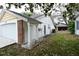 Rear exterior of a house featuring a two-car garage, white siding, and a fenced backyard with trees at 12411 Yorktown Ln, Hudson, FL 34667