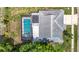 Aerial view of a home with a screened-in pool, solar panels, a gray roof and mature trees at 13003 Sandburst Ln, Hudson, FL 34667