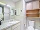Bright bathroom featuring tiled walls, vanity with marble countertop and storage cabinet and a toilet with wall-mounted shelving at 13003 Sandburst Ln, Hudson, FL 34667